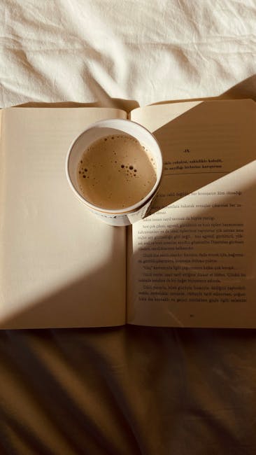 A cup of coffee placed on an open book in warm morning light.